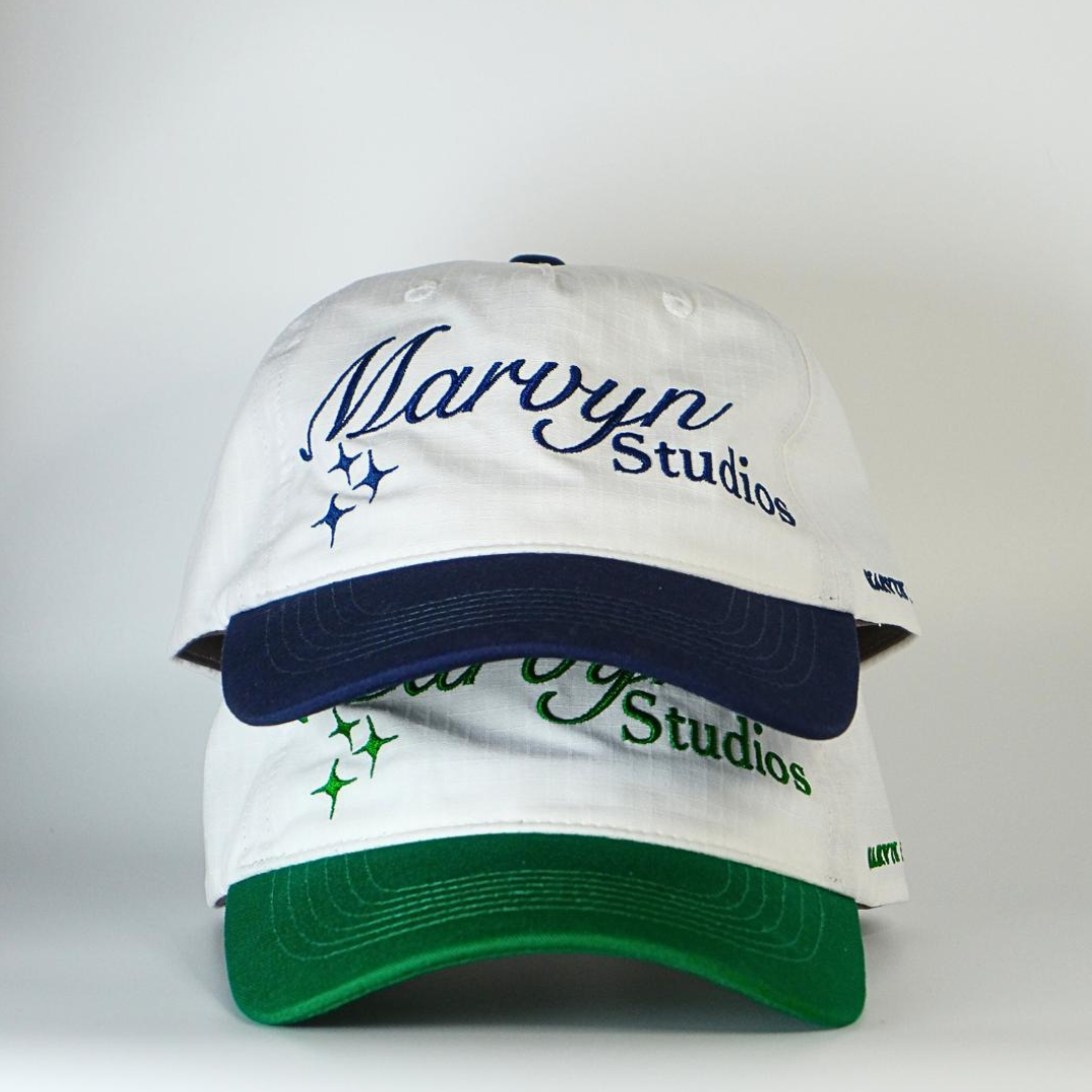 White cap with blue and green accents featuring 'Marvyn Studios' branding on a white background