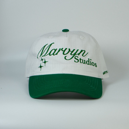 White cap with green brim and embroidered text on a white background