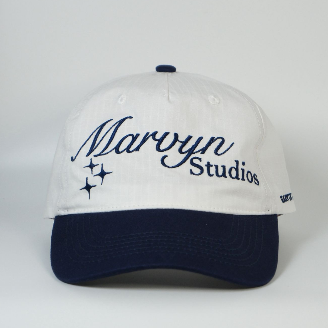 White cap with navy blue brim and embroidered text on a white background